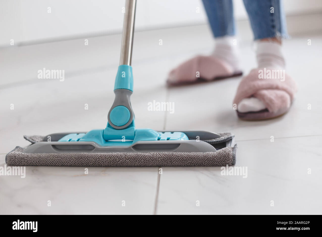 Housewife mopping floor made of porcelain tiles in the kitchen. Stock Photo