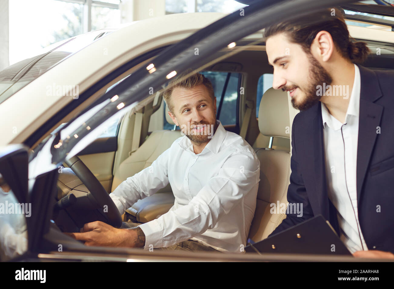 Auto dealer shows a new car to a man Stock Photo