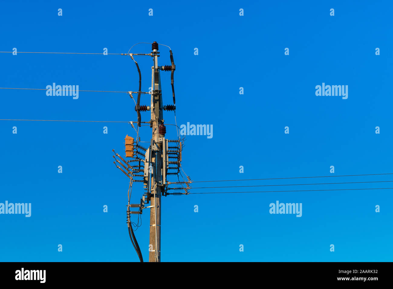 Medium voltage disconnectors on electricity pylon. Power line pole with wires and isolator switches on blue sky background. For safe service or repair Stock Photo
