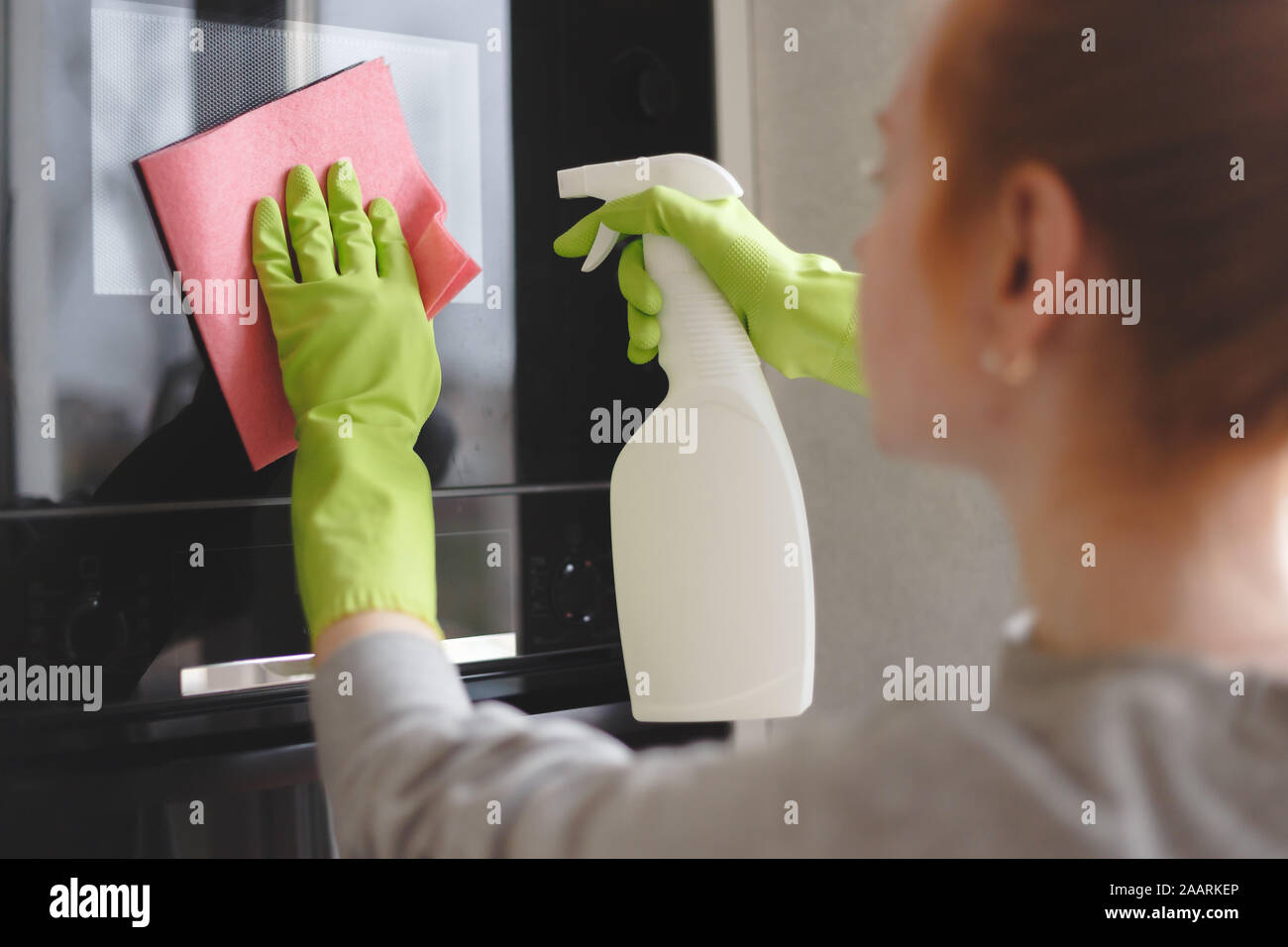 Woman cleaning oven and microwave with rag in kitchen, close up Stock Photo