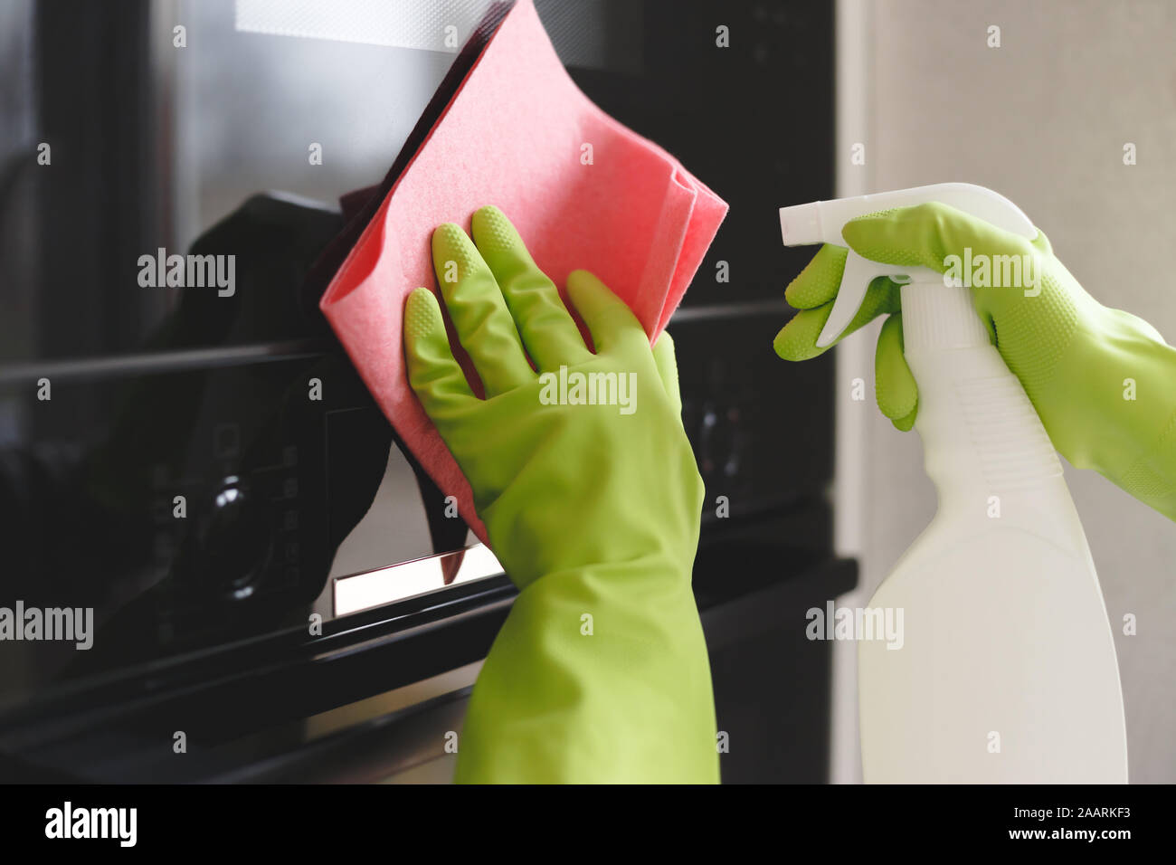 Woman cleaning oven and microwave with rag in kitchen, close up Stock Photo