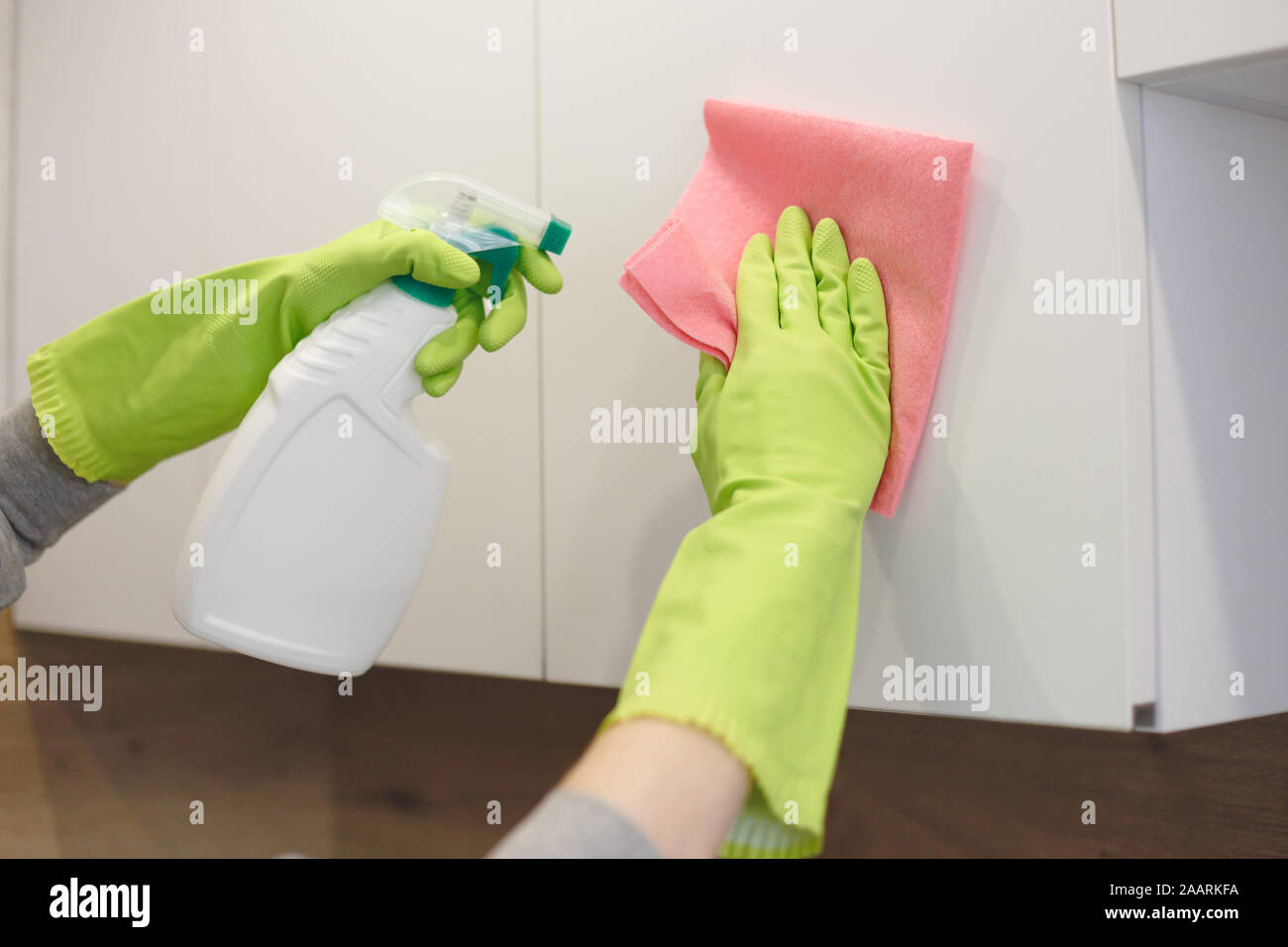 Woman Is Cleaning Kitchen Cabinet Door With Rag And Spray