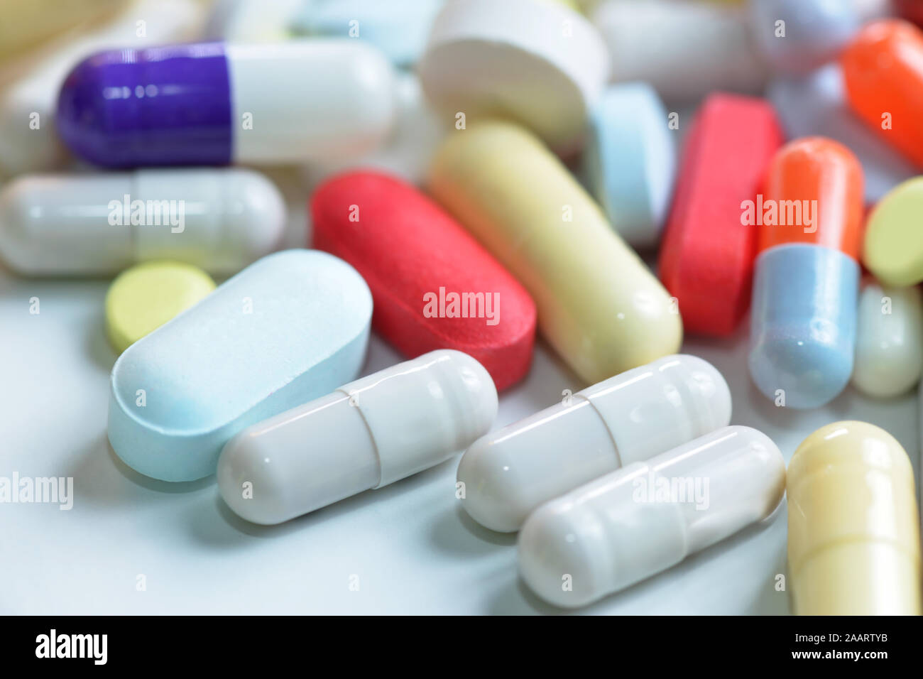 Colorful tablets and assorted capsules spill on neutral background. Stock Photo