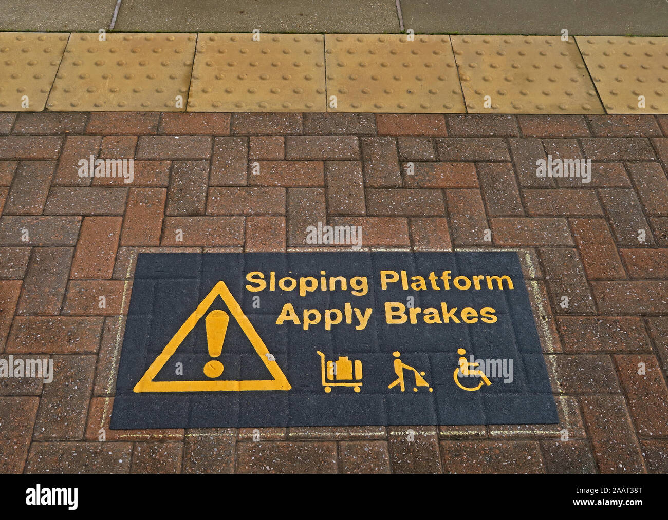 Sign Sloping Platform Apply Brakes sign,luggage, prams, disabled on platform, Warrington Bank Quay Station, WA1 1LW Stock Photo