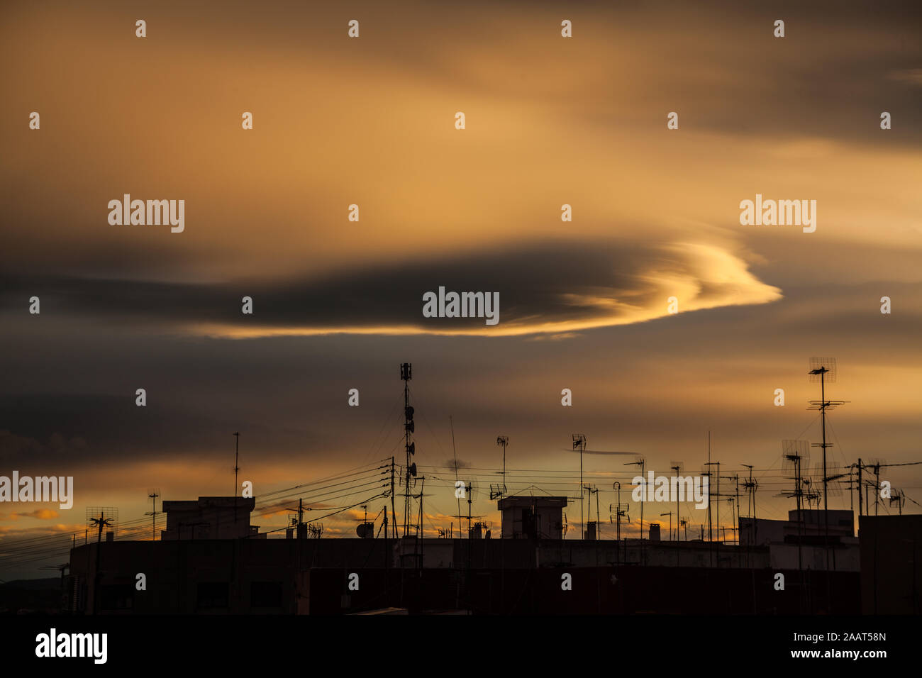 Dramatic brown sky with clouds over rooftops with antennas at sunset Stock Photo
