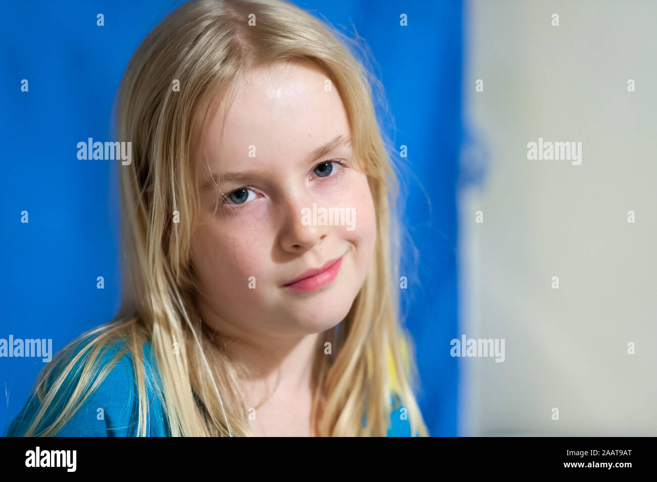 Pretty young blonde girl with blue eyes and an enigmatic smile Stock Photo