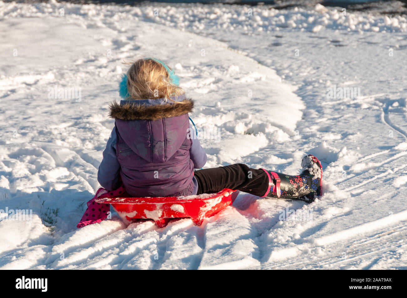 View from behind of young girl sledging Stock Photo