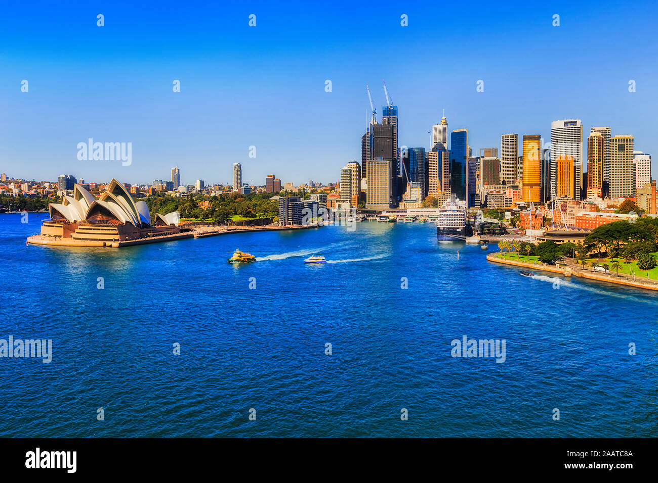 Landmarks of Sydney city on shores of Sydney harbour seen from elevation of the Harbour bridge towards Circular quay ferry wharves and high-rise offic Stock Photo