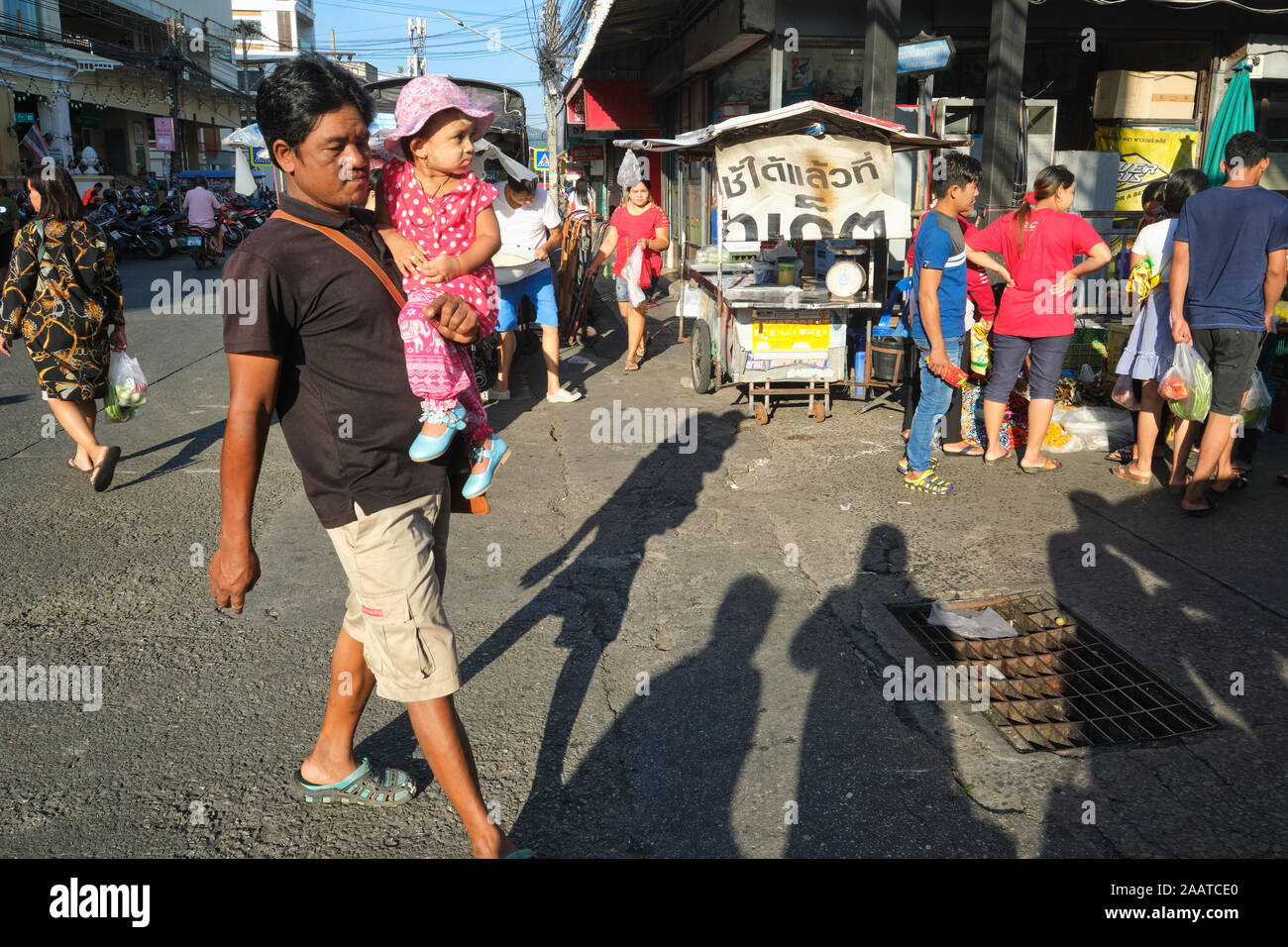 A male migrant worker from Myanmar (Burma) with his child,  out for Sunday shopping in the main market in Phuket Town, Phuket, Thailand Stock Photo