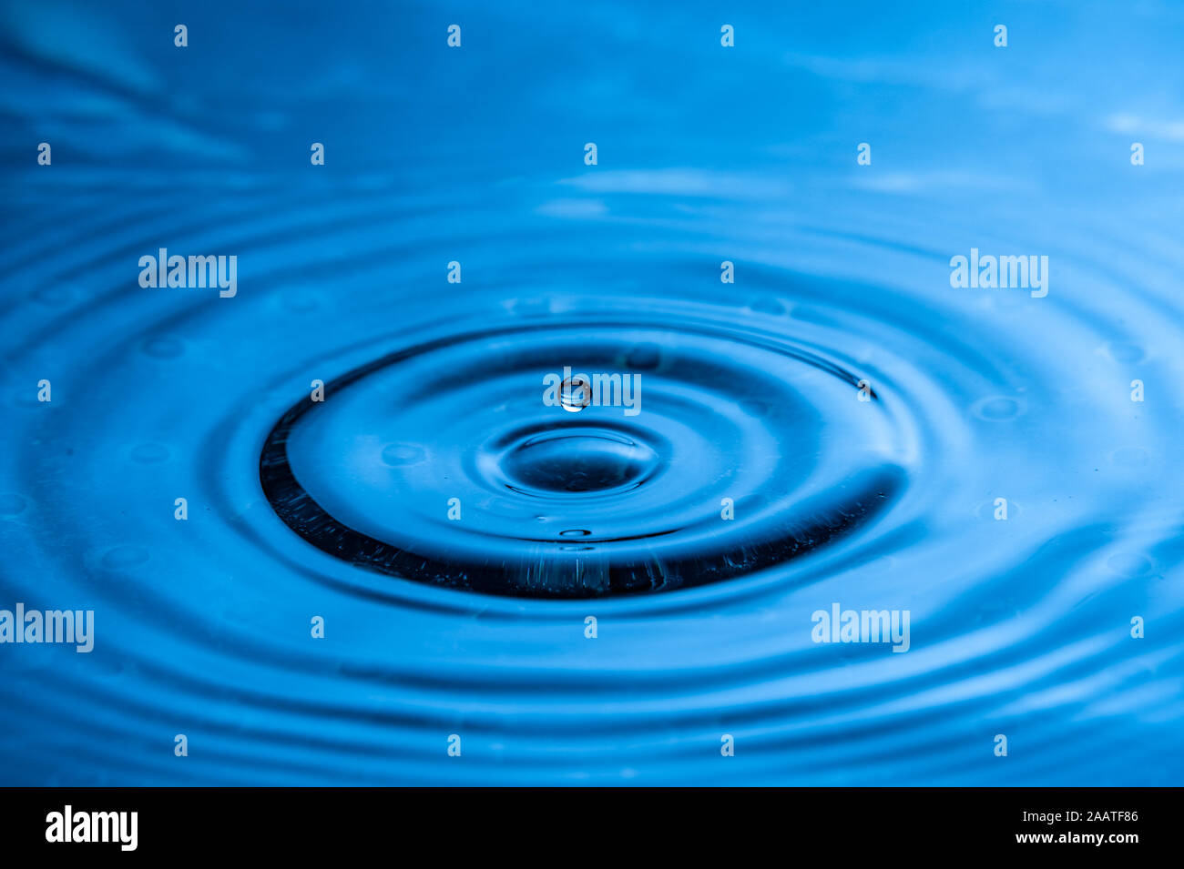 High speed water drop photography. Blue with single drop about to splash Stock Photo