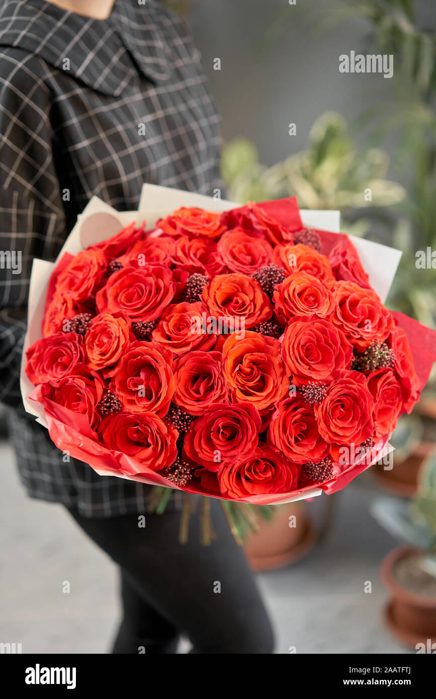 Mono bouquet of red roses in womans hands. European floral shop. the work of the florist at a flower shop. Delivery fresh cut flower. Stock Photo