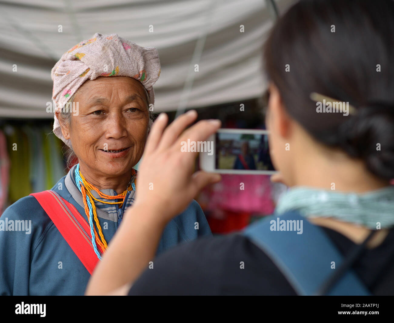 Japanese portrait photographer uses her iPhone for a quick test shot of an elderly Thai Karen tribal woman with betel-nut stained lips. Stock Photo