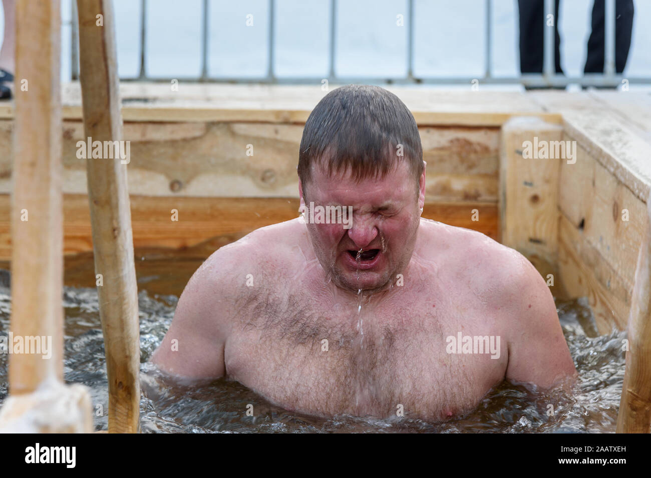 Man bathes into cold water of ice-hole on Epiphany day. Traditional ice swimming in Orthodox church Holy Epiphany Day. Russia Stock Photo