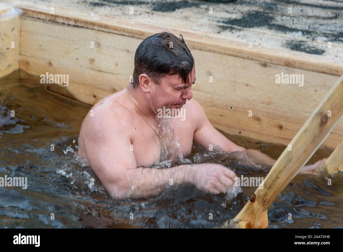 Man bathes into cold water of ice-hole on Epiphany day. Traditional ice swimming in Orthodox church Holy Epiphany Day. Russia Stock Photo