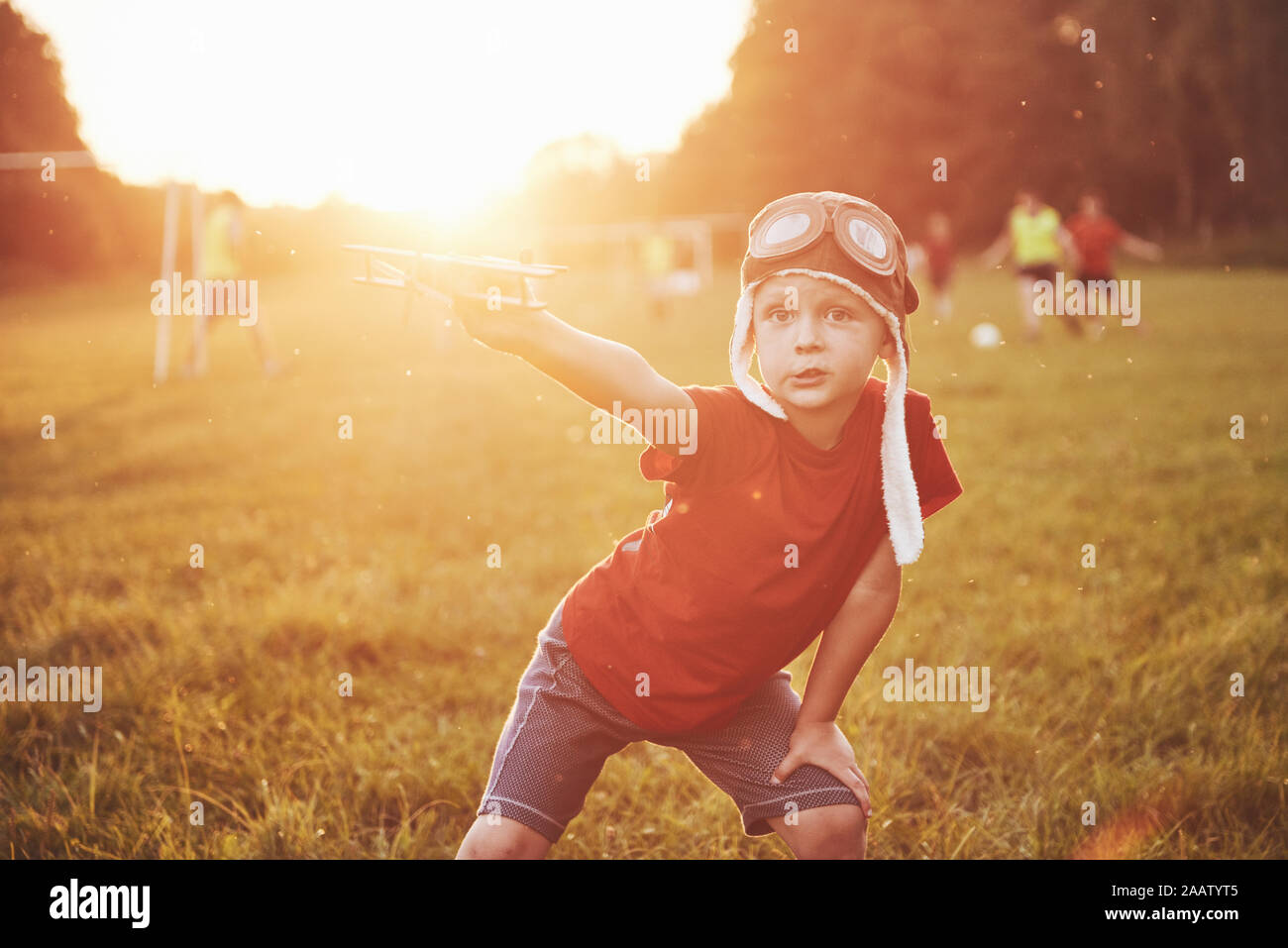 Happy kid in pilot helmet playing with a wooden toy airplane and ...