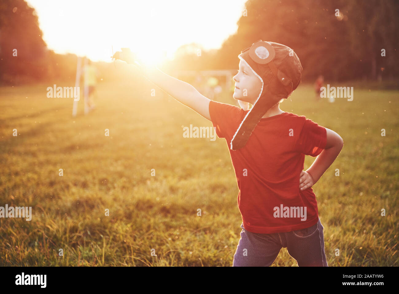 Happy kid in pilot helmet playing with a wooden toy airplane and ...