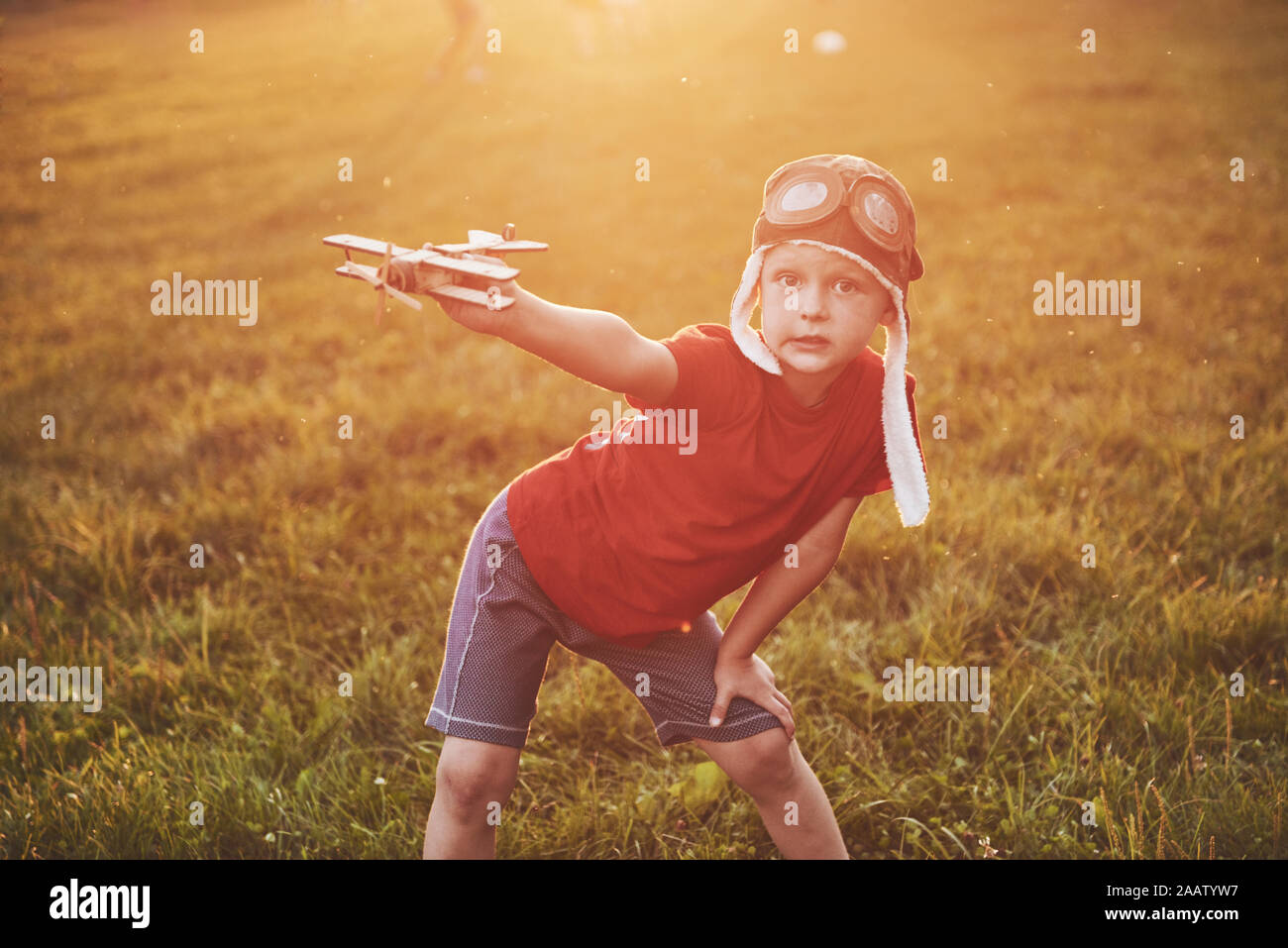 Happy kid in pilot helmet playing with a wooden toy airplane and ...