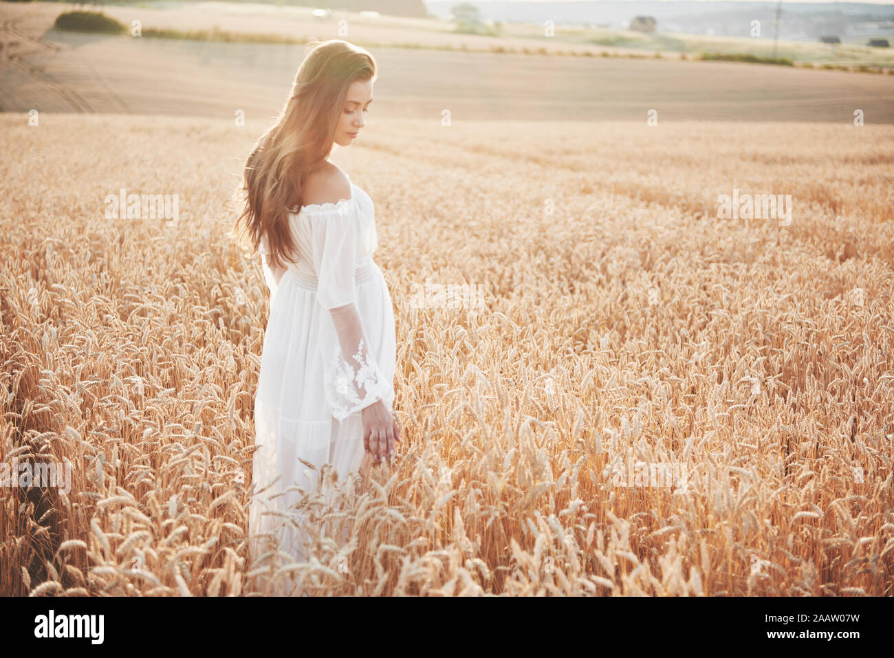 Happy young girl with long, beautiful hair standing in a wheat field ...