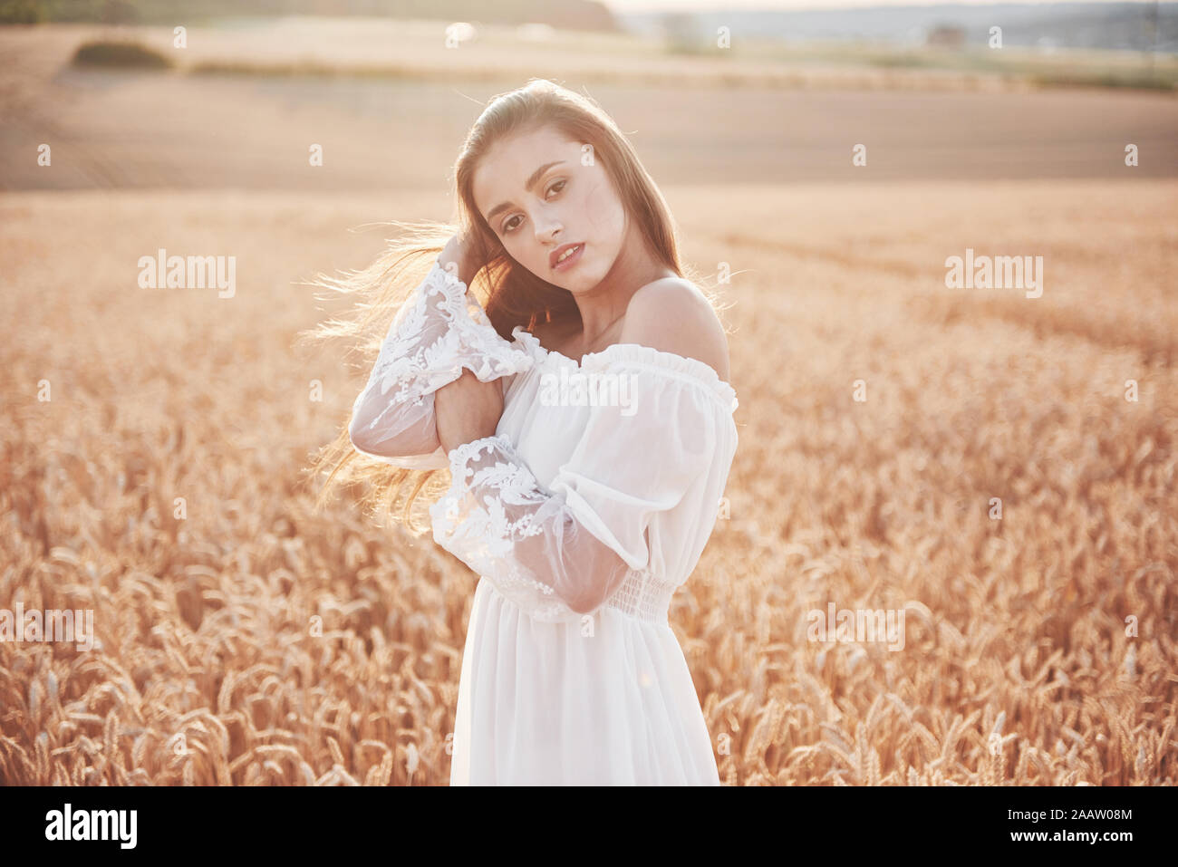 Portrait of a beautiful girl in a white dress in the field of wheat ...