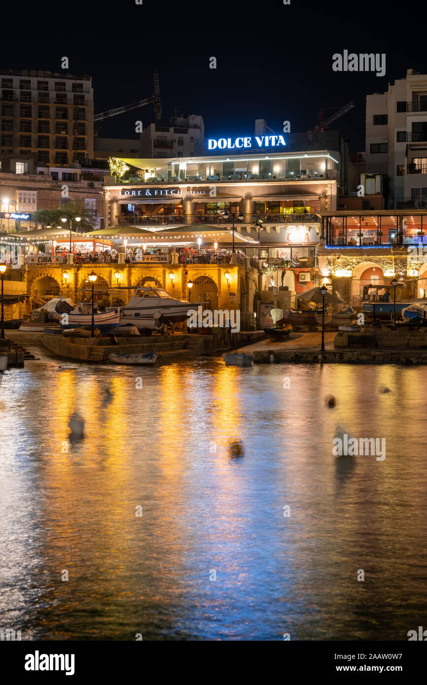 Paceville, St Julian town in Malta by night, restaurants in popular nightlife hotspot from Spinola Bay Stock Photo