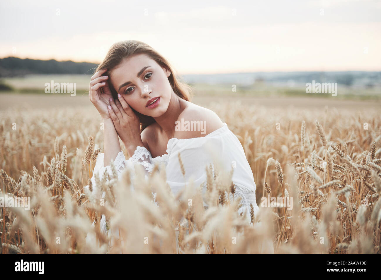 Beautiful girl in a field of wheat in a white dress, a perfect picture ...