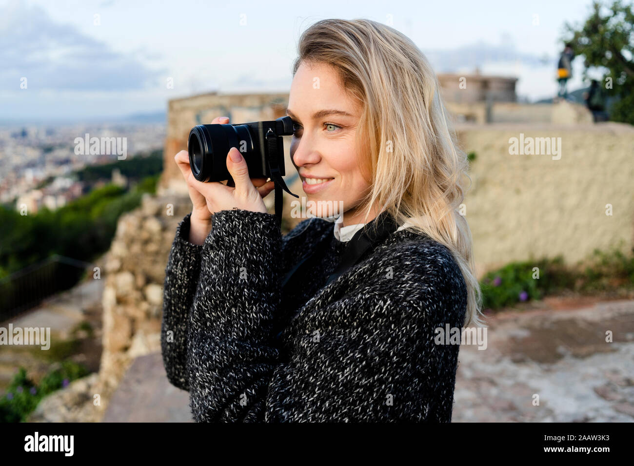 Young woman taking pictures above the city at sunrise, Barcelona, Spain Stock Photo