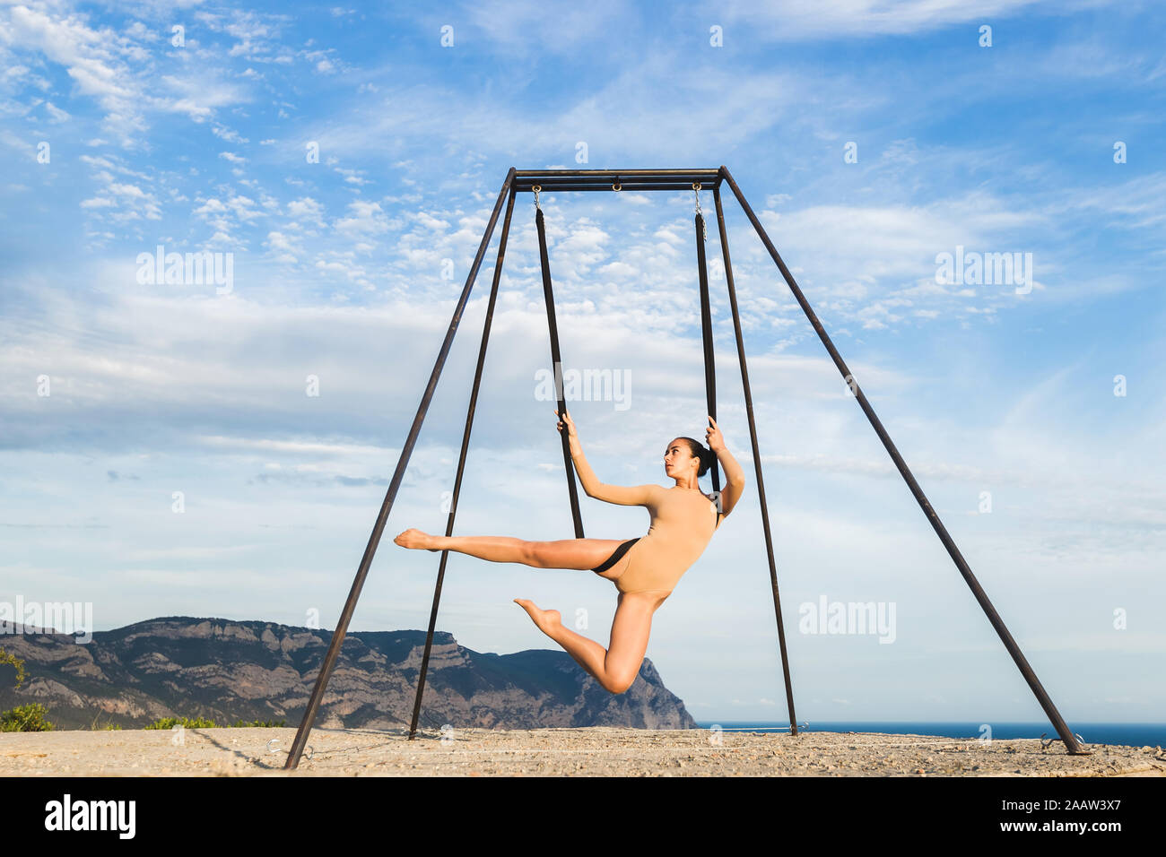 Woman practicing fly dance gravity yoga poses in a hammock outdoors with mountain view. Healthy lifestyle, active woman. Stock Photo