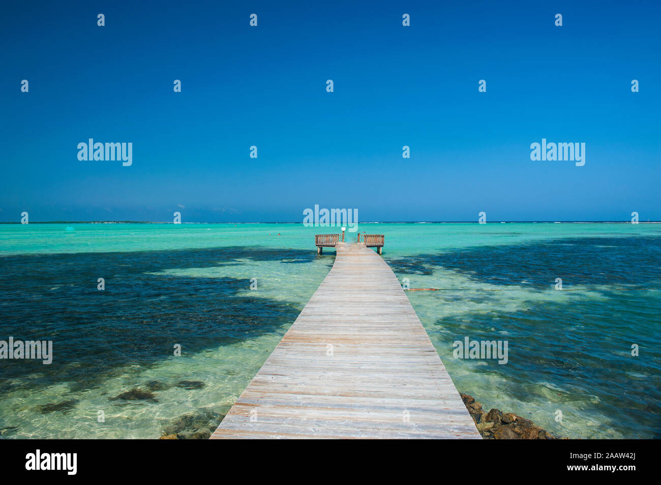 Diminishing perspective of pier in Lac Bay against clear blue sky at Bonaire, Netherlands Antilles Stock Photo