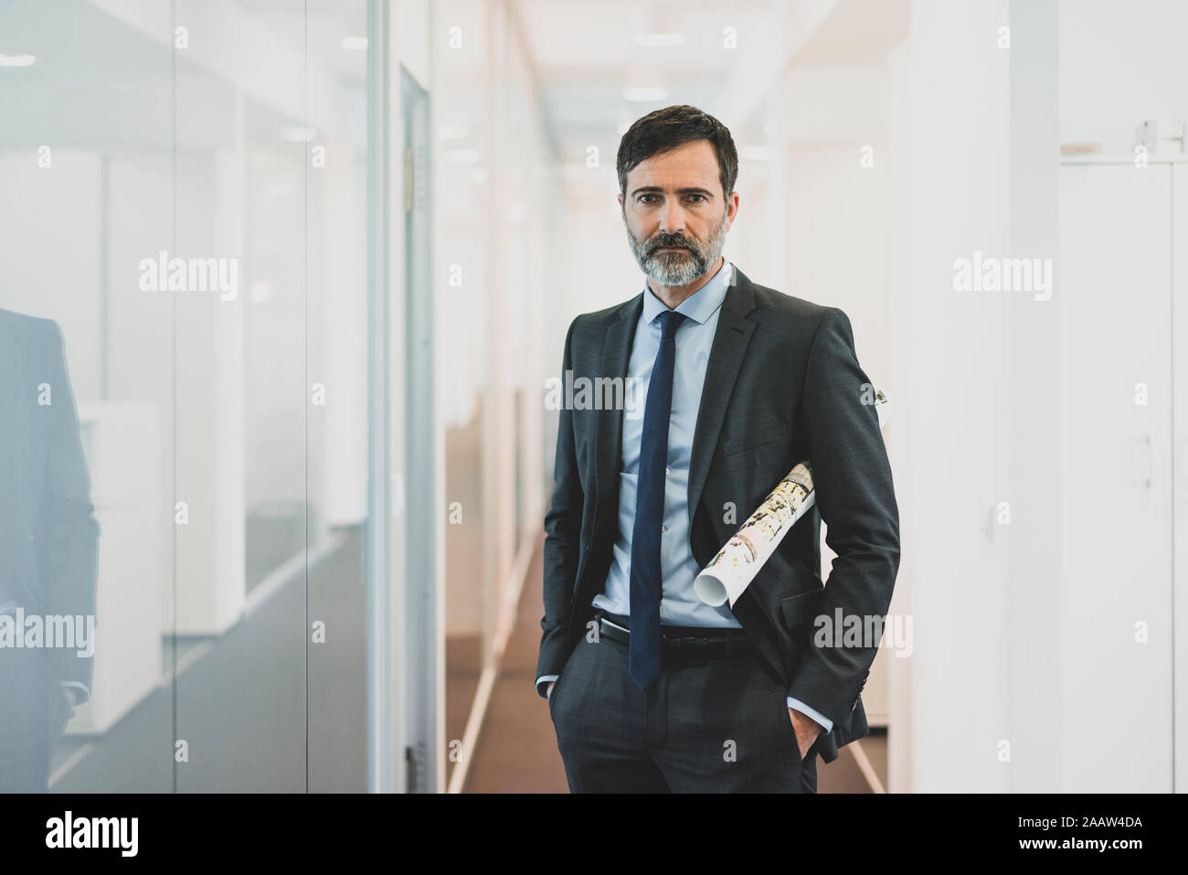 Portrait of serious mature businessman standing on office corridor Stock Photo