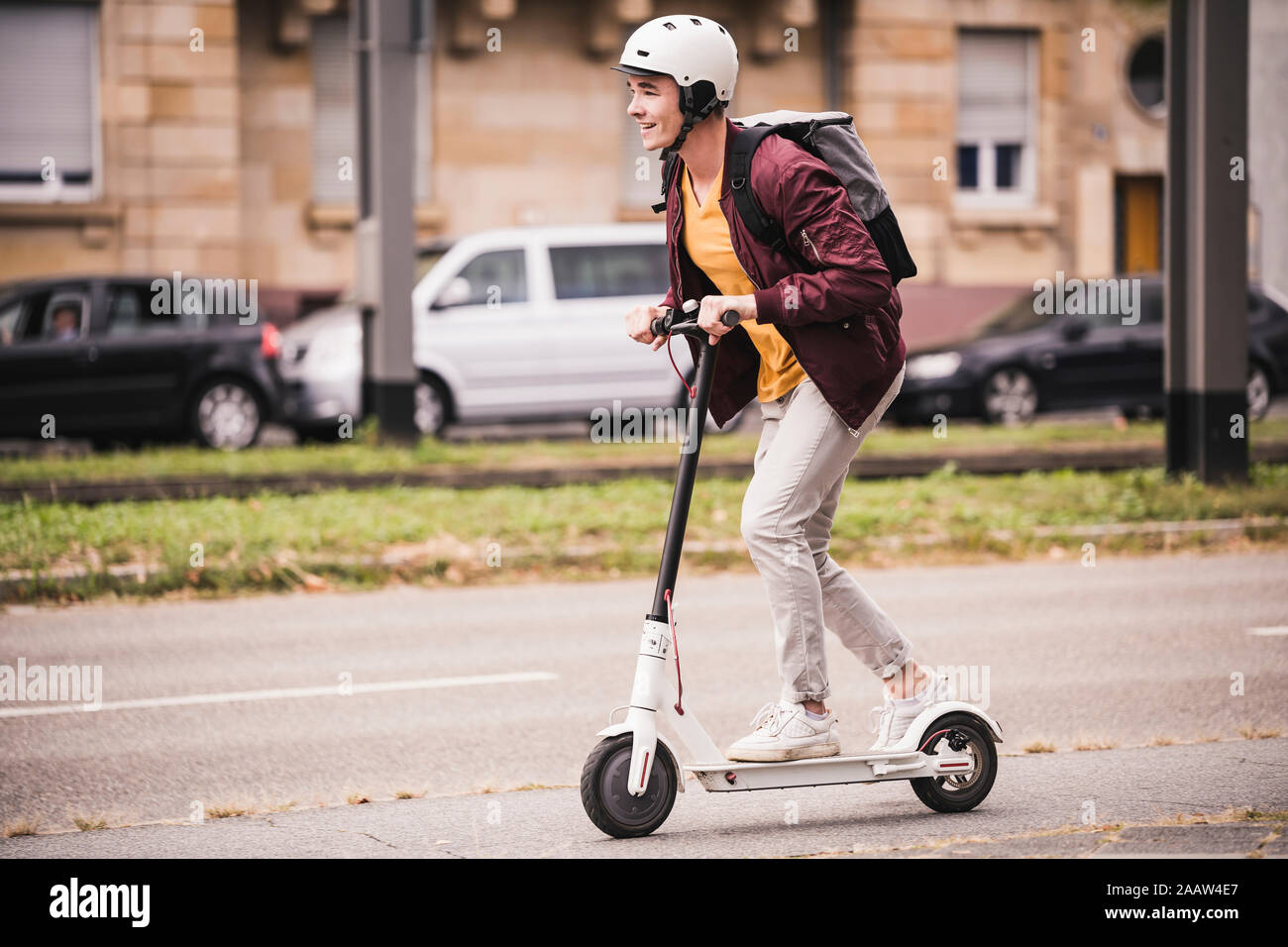 Smiling young man riding scooter in the city Stock Photo