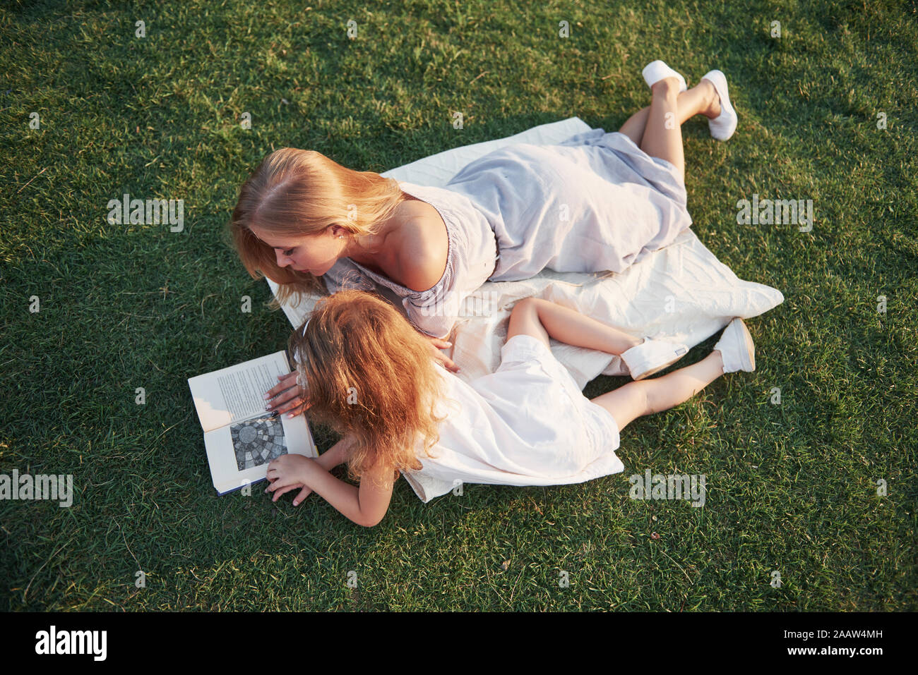 mother with a child reads a book on the grass Stock Photo