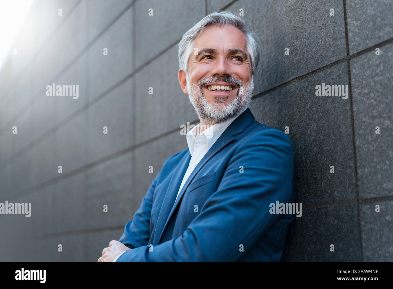 Portrait of smiling mature businessman at a wall Stock Photo