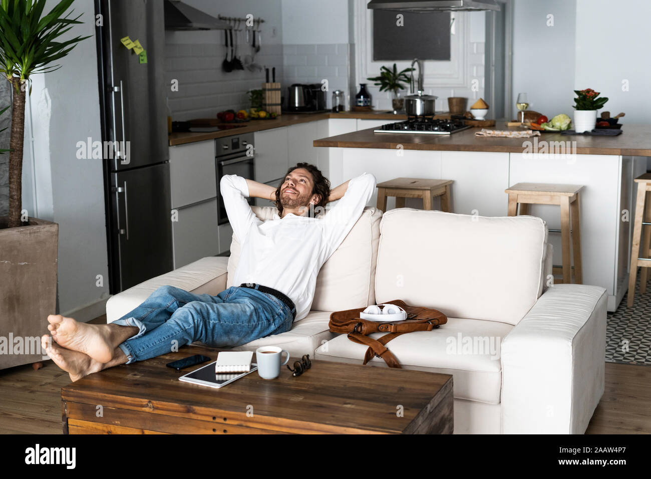 Relaxed man leaning back on couch at home Stock Photo