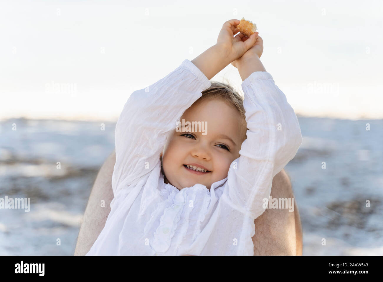 Cute toddler girl on the beach lying on father's legs Stock Photo