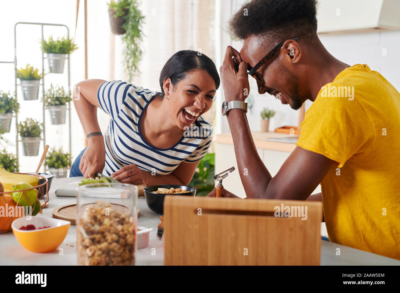 Multiethnic couple laughing, breakfasting together in the kitchen Stock Photo
