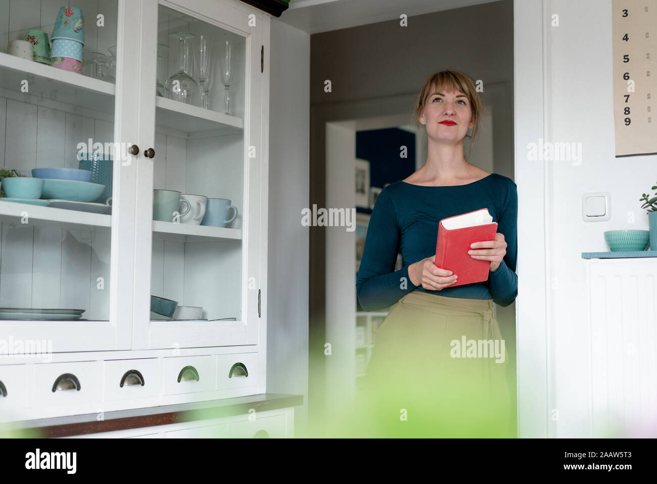 Portrait of woman with novel lening against door case at home Stock Photo