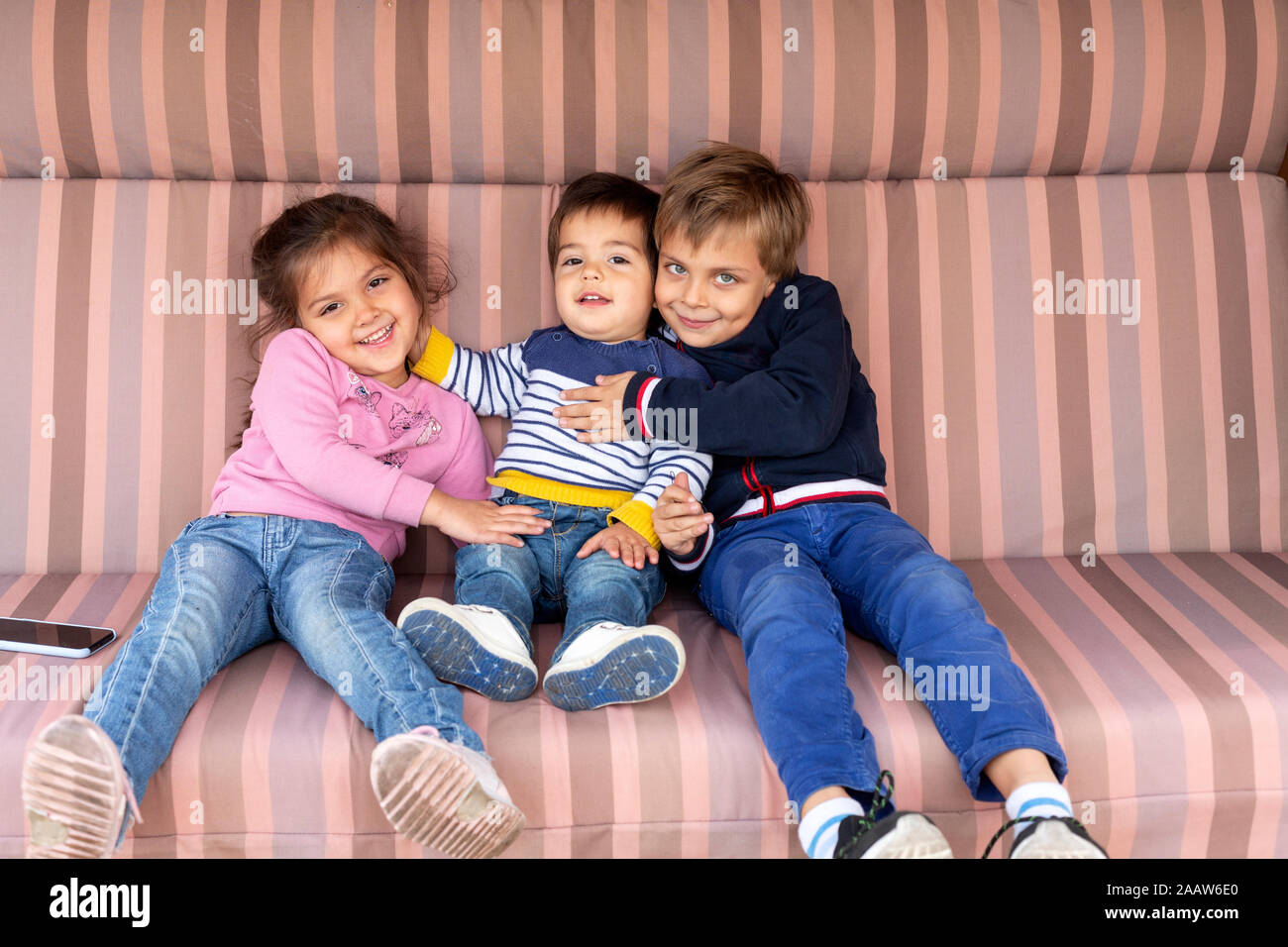 Portrait of three siblings sitting side by side Stock Photo