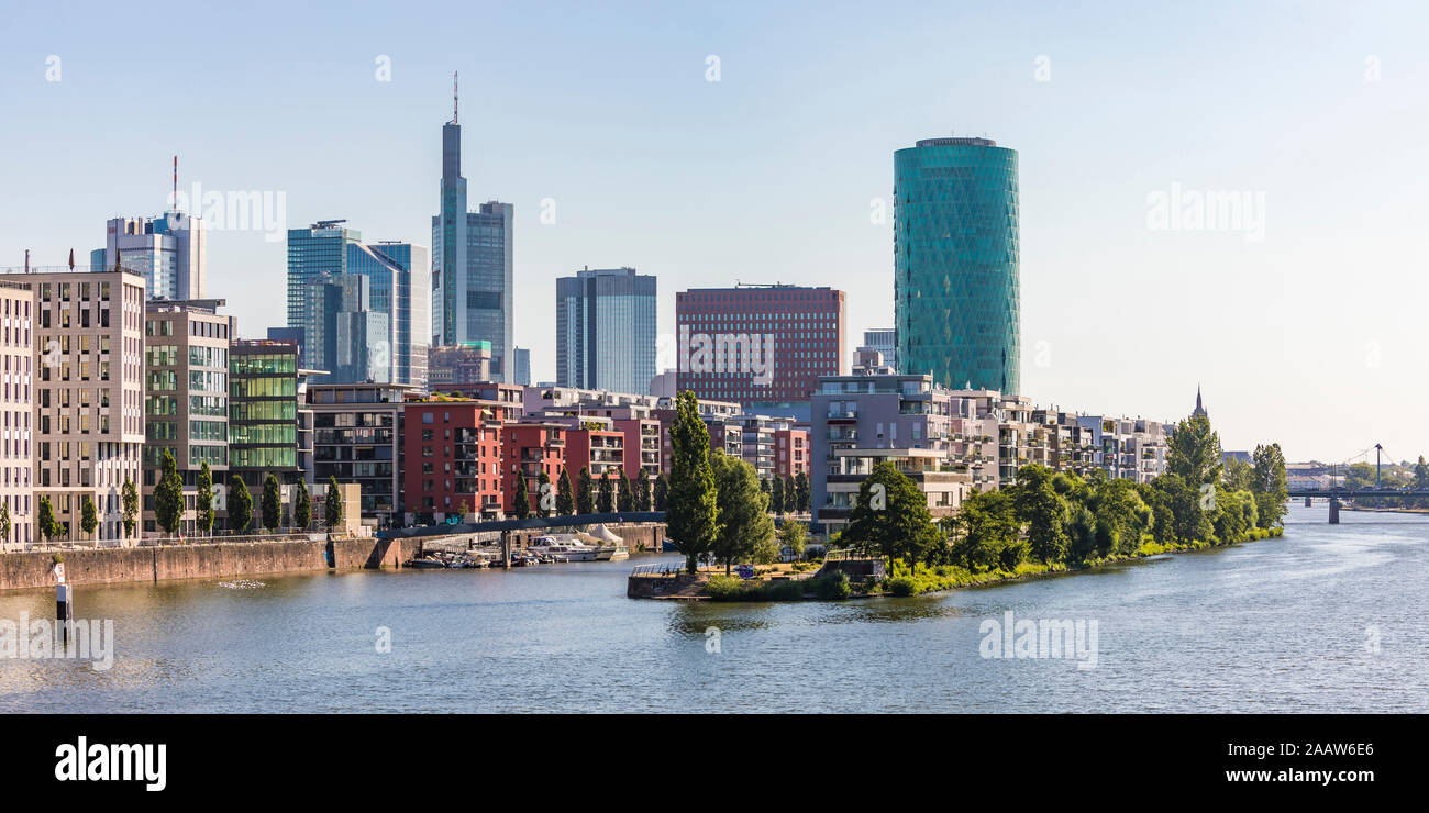 Buildings and Westhafen Tower by river against clear sky in Frankfurt, Germany Stock Photo