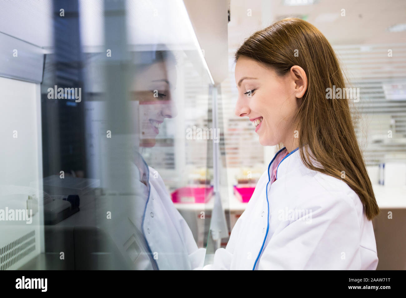 Side view of female scientist in white apparel working in modern laboratory Stock Photo