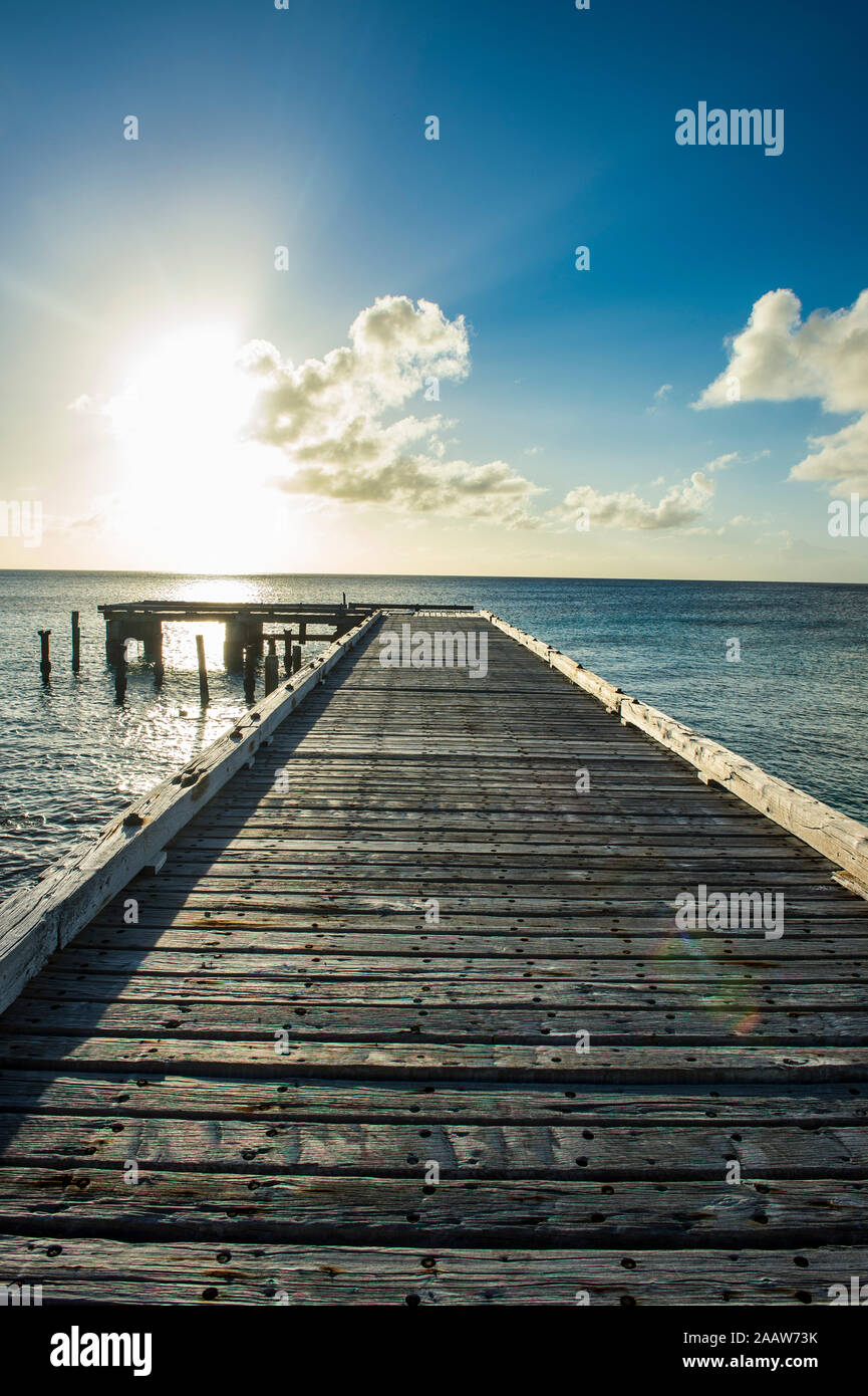 Diminishing perspective of pier over sea against sky at sunset, Cockburn town, Grand Turk Stock Photo