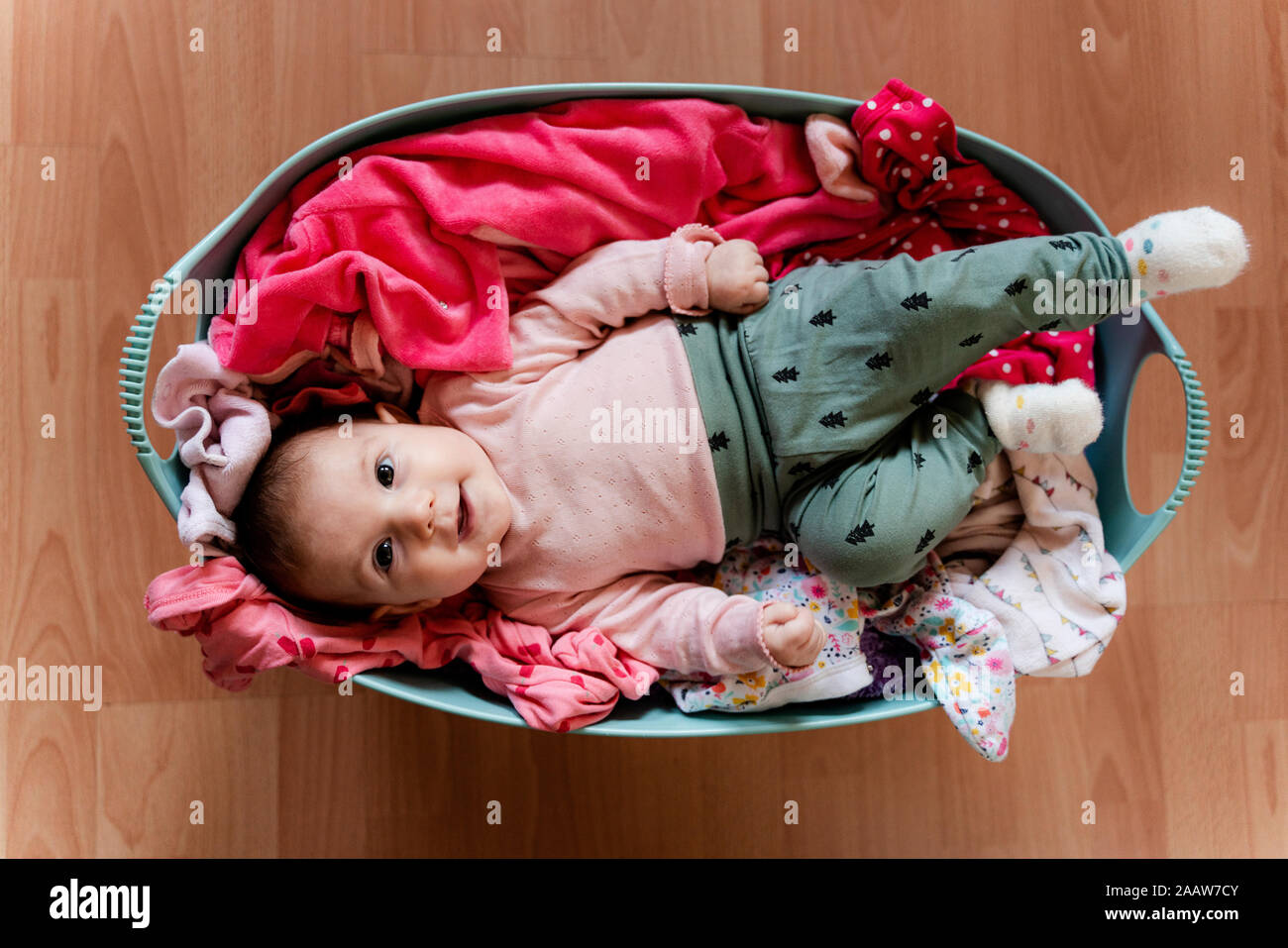 Baby girl in the laundry basket with clothes to clean Stock Photo