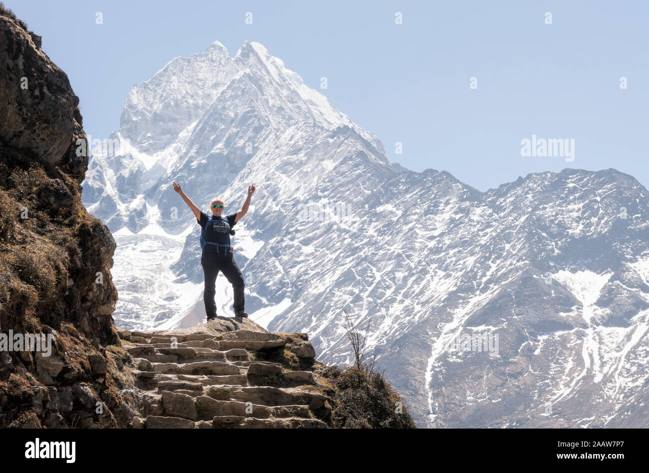 Happy woman raisng arms in front of Thamersku mountain, Himalayas, Solo Khumbu, Nepal Stock Photo