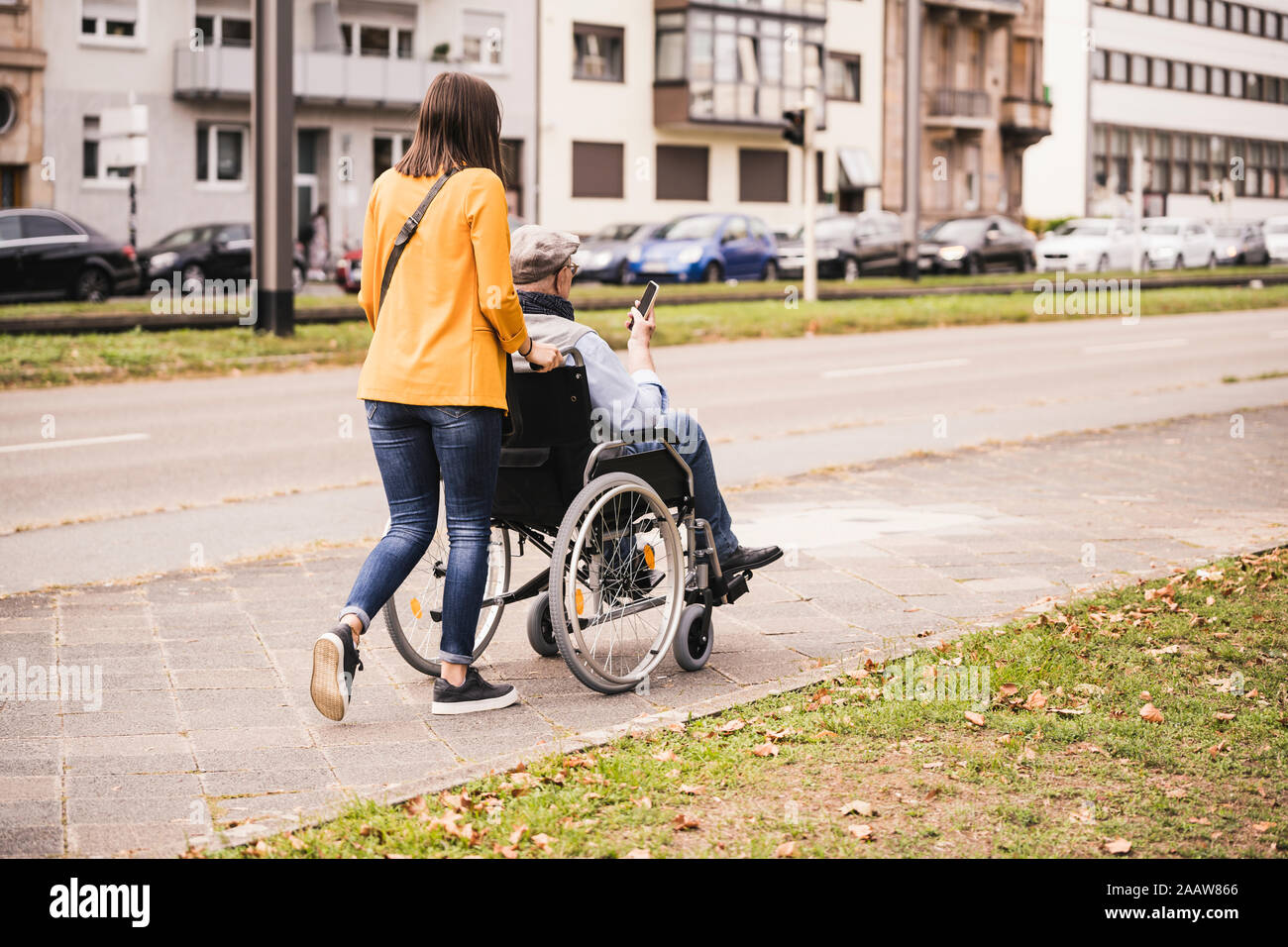 Pushing Back View Back view of young woman pushing senior man with smartphone in ...