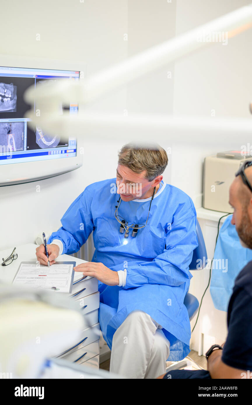 Dentist surgeon chatting with patient writing in blog Stock Photo