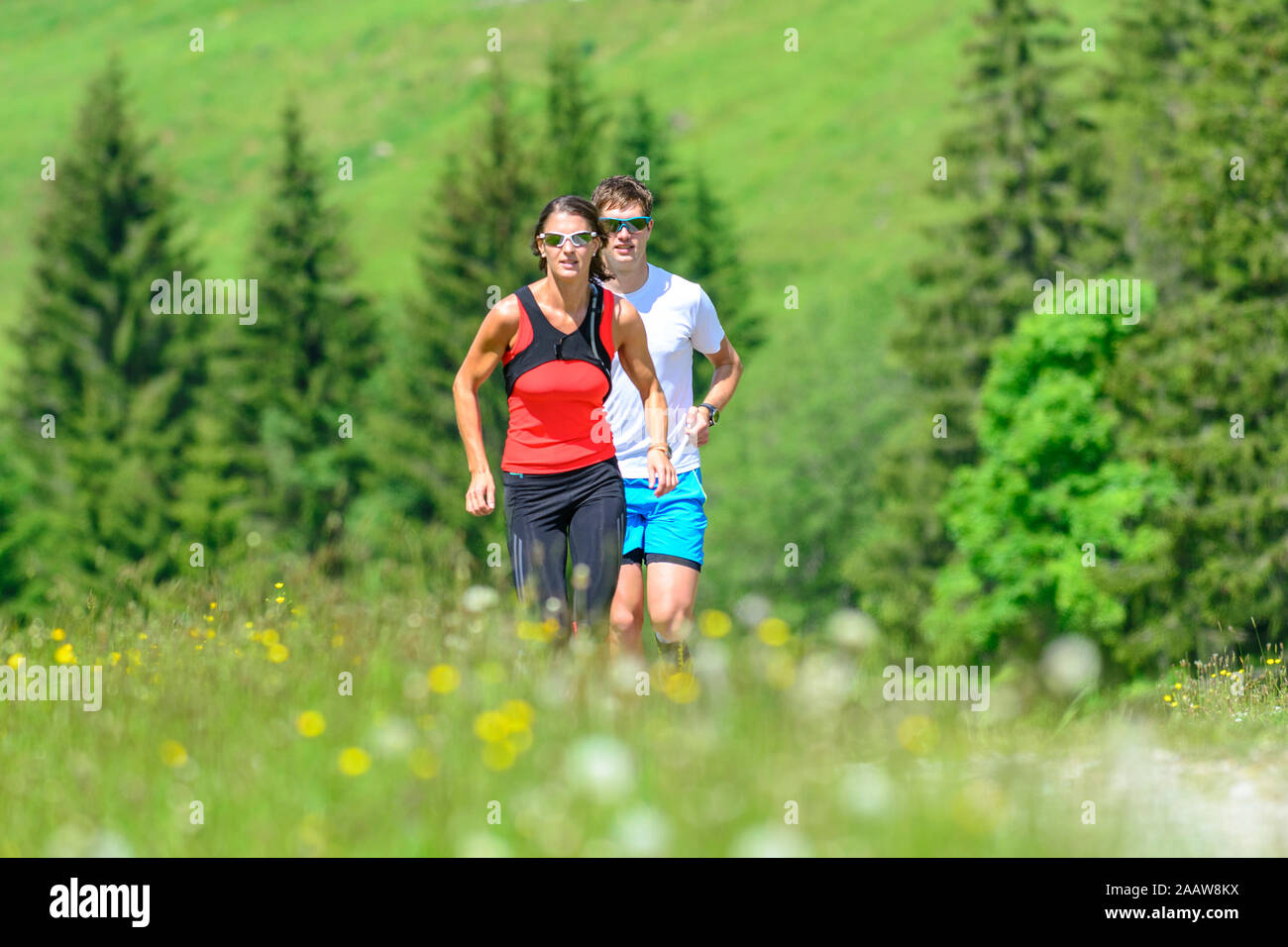 Young people doing a running session in green alpine nature Stock Photo