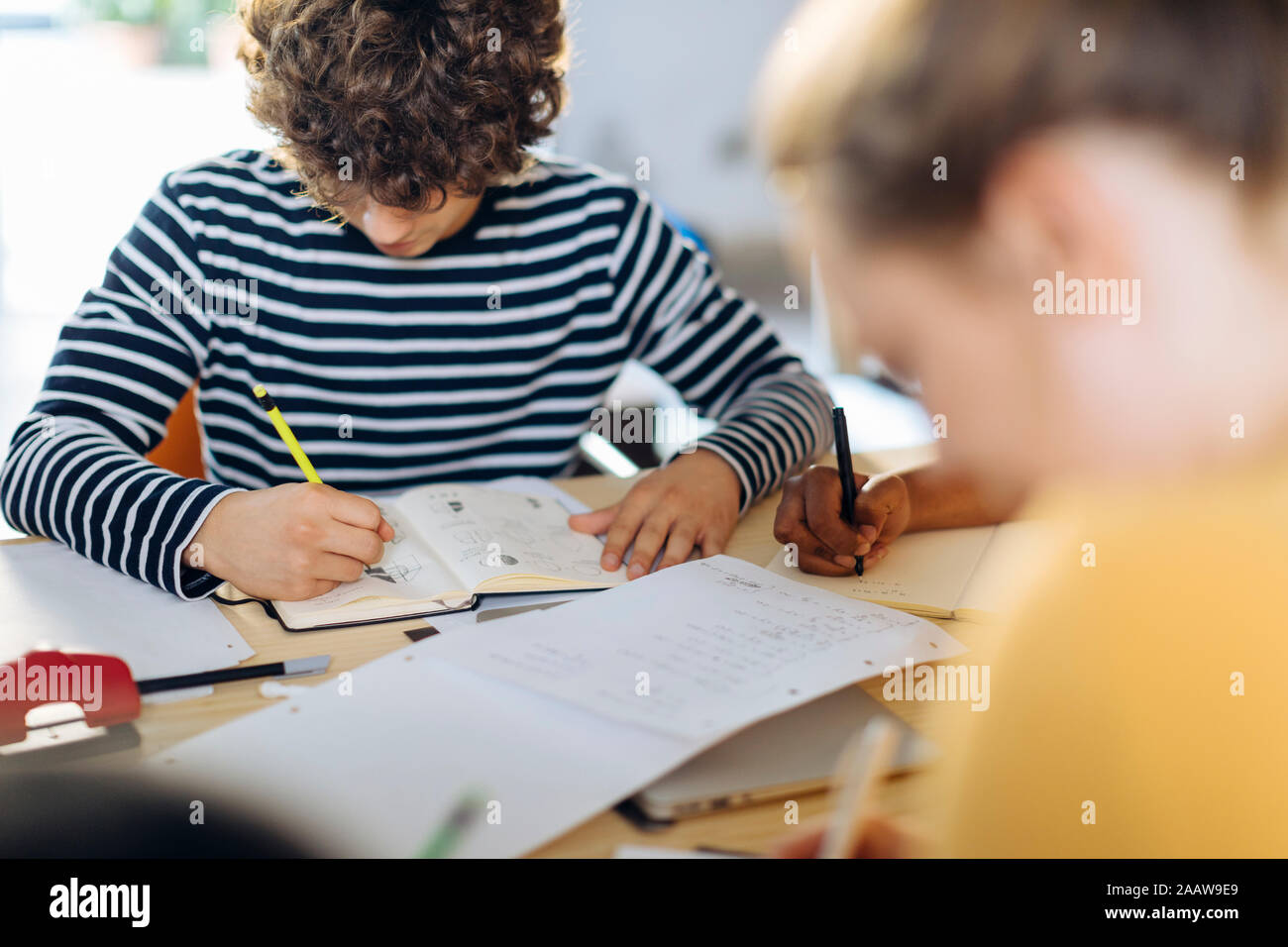 Young people sitting together at table and taking notes Stock Photo