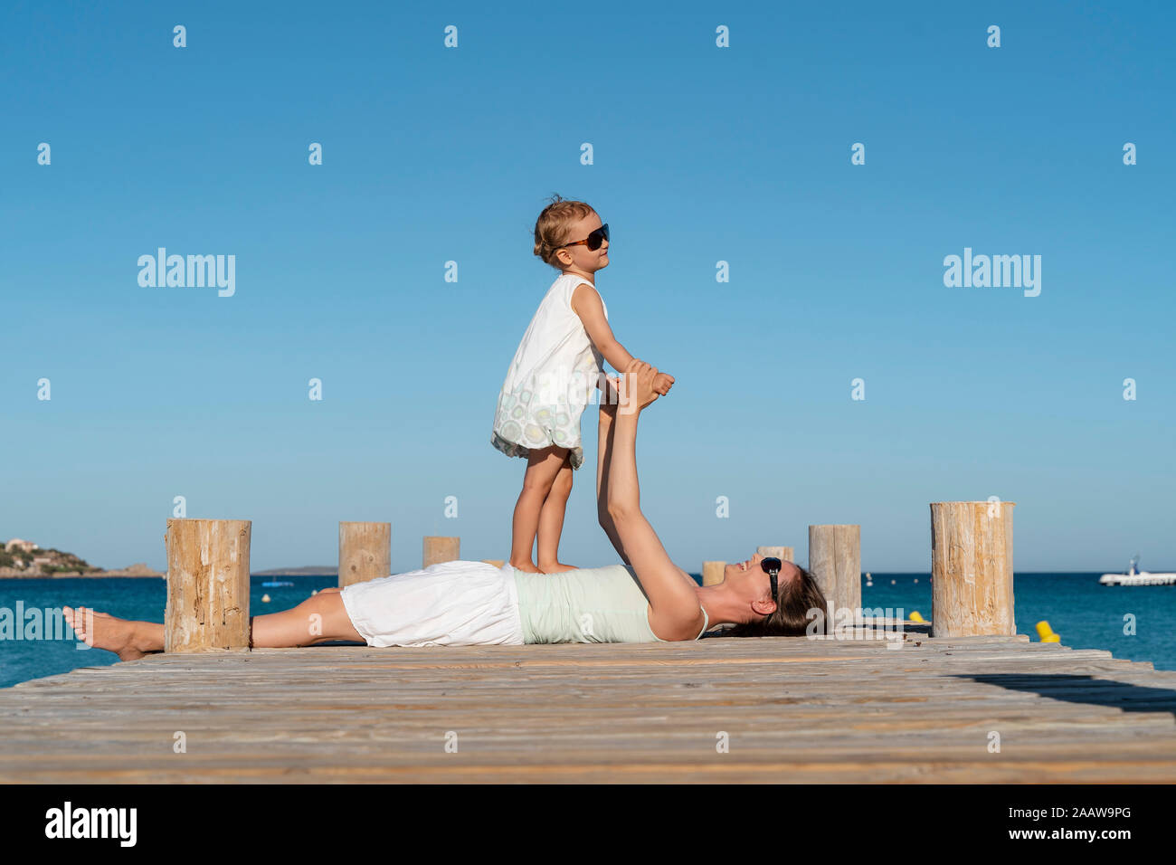 Happy mother lying with daughter on a jetty at the sea Stock Photo