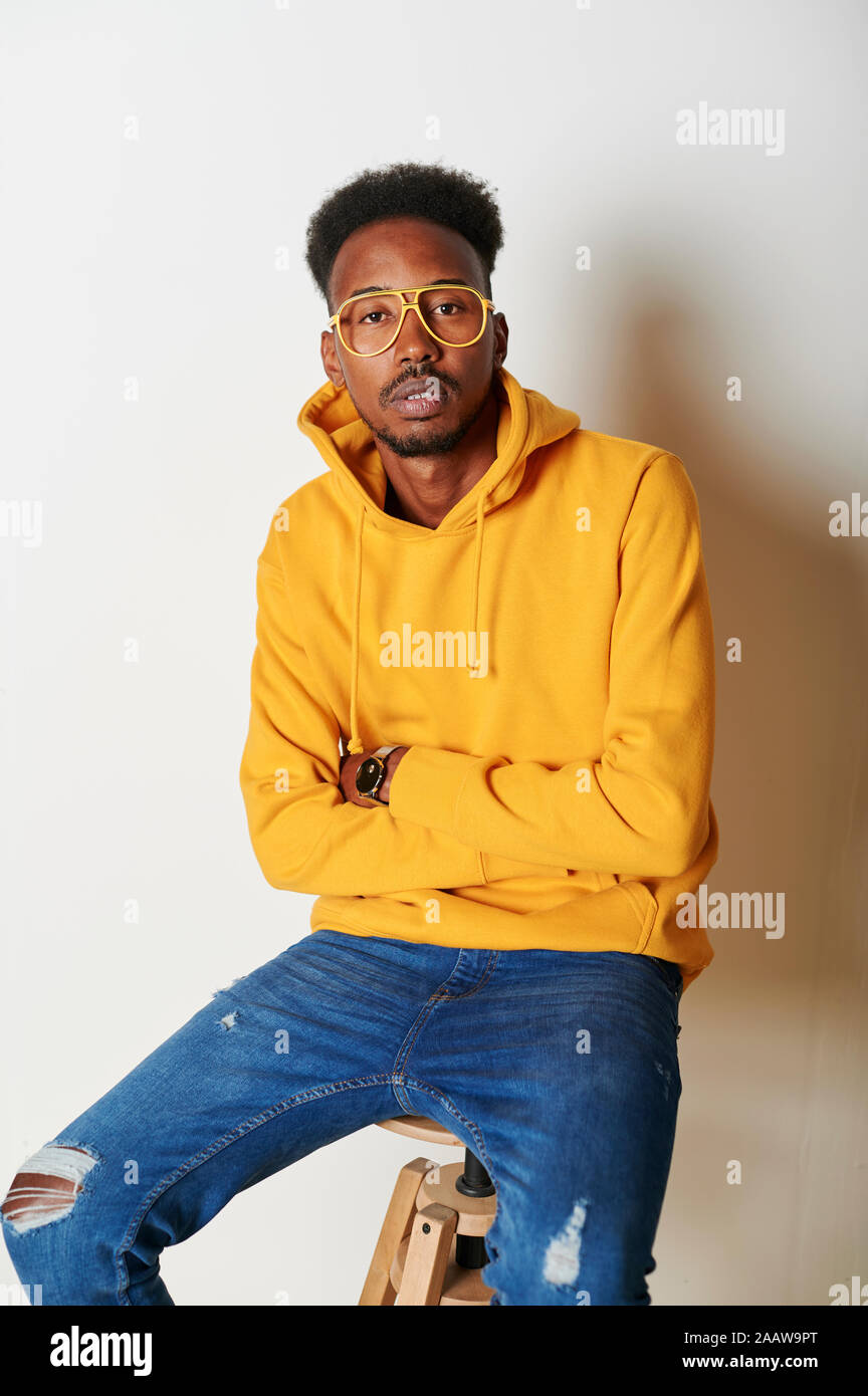 Young man wearing yellow hoodie sweater and glasses Stock Photo