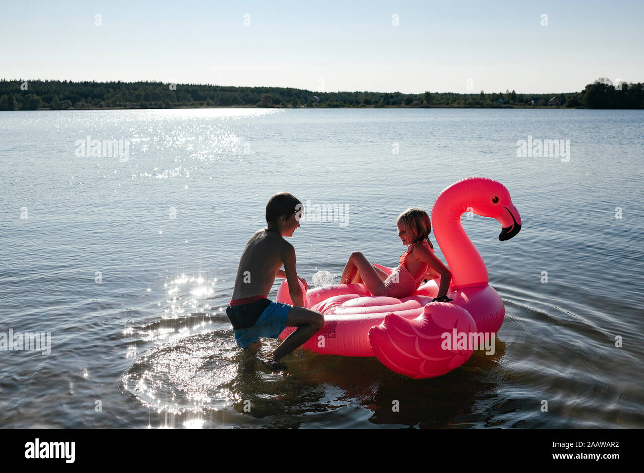 Brother and sister with flamingo pool float on the lake Stock Photo