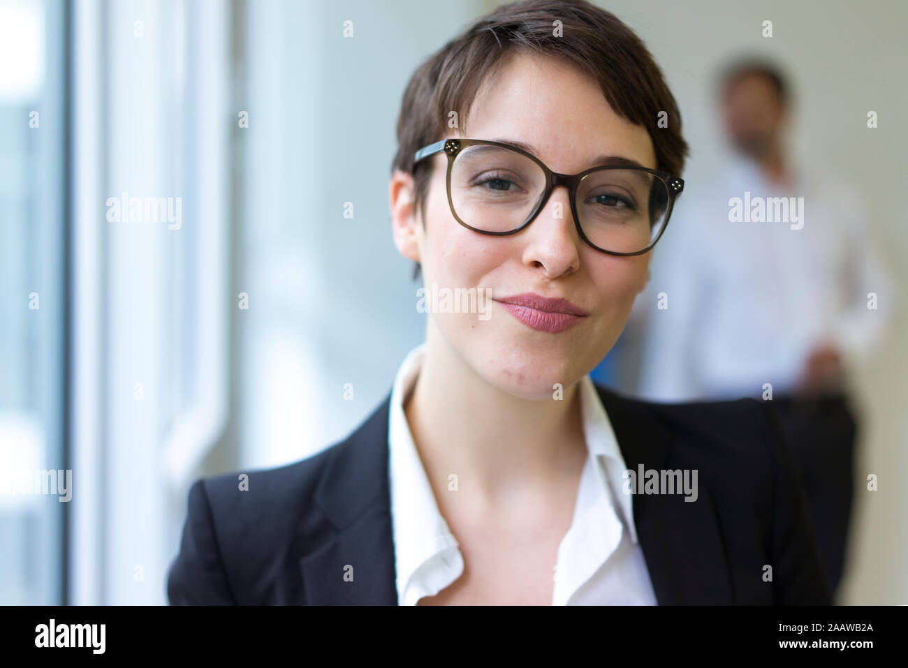 Portait of confident young businesswoman with man in background Stock Photo